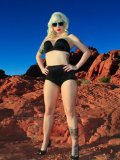 Blonde haired alternative model Lynn Pops dressed in black poses in the mountains