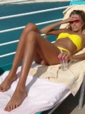 Lori Anderson in pink shades and yellow bikini demonstrates her hairy arms in the sun