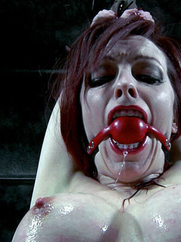 Ball gagged slave redhead Emily Marilyn with big round melons is helpless in restraints