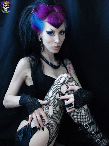 Blue-haired gothic model Razor Candi dressed in back shows her private parts