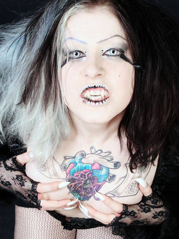 Gothic Mad Sophie dressed in black exposes her tattooed chest and shaved snatch