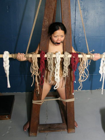 Oriental Angela Decorative with small tits and hairless snatch gets tied to special construction