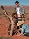 Slutty Amber Rayne is gagged, tied up and pinched with pegs in the desert where she sucks two dicks