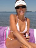 Lori Anderson in white bikini demonstrates her hairy arms as she rubs tanning oil on her skin